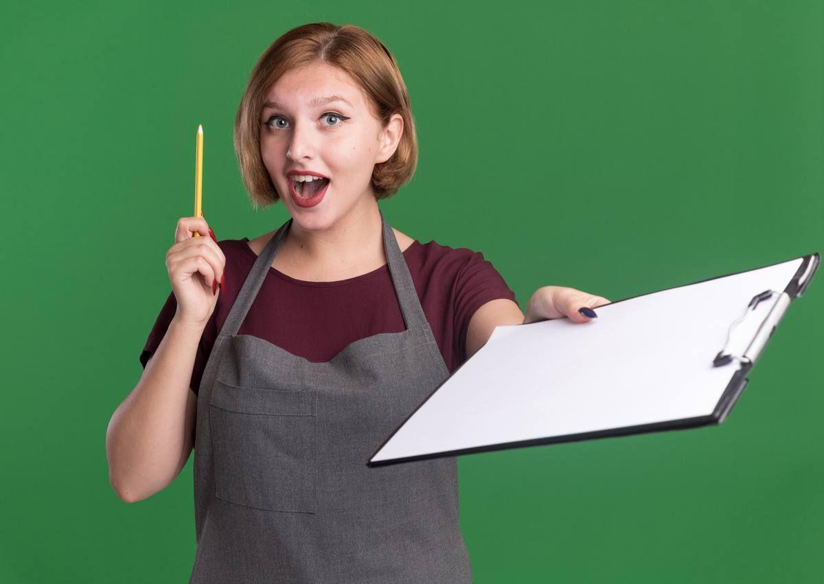 young-beautiful-woman-hairdresser-apron-holding-pencil-showing-clipboard-looking-front-surprised-happy-having-new-idea-standing-green-wall.jpg